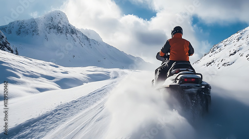 A snowmobile rider powering through a snow-covered mountain pass with snow kicking up behind as they accelerate through the terrain. photo