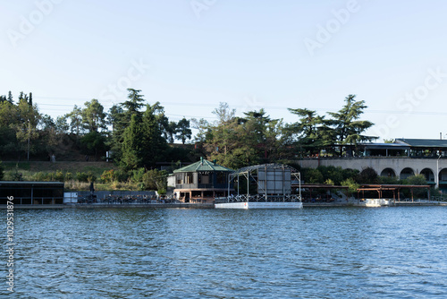 lake with blue water, and trees and buildings on the shore, Turtle Lake in Tbilisi