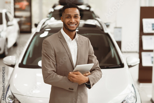 Smiling Car Dealer Standing Near Luxury Automobile Holding Folder Working In Auto Selling Showroom. Vehicle Dealership Concept