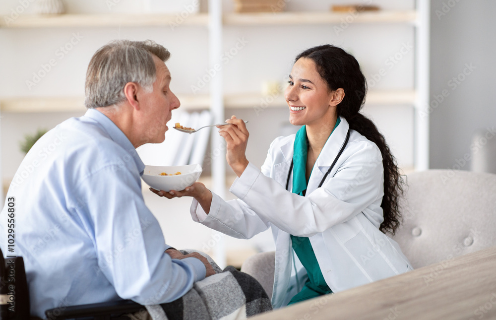 © Prostock-studio - Medical assistance for elderly people with disabilities. Young nurse feeding senior handicapped man in wheelchair at home. Older male patient eating breakfast with caregiver's help