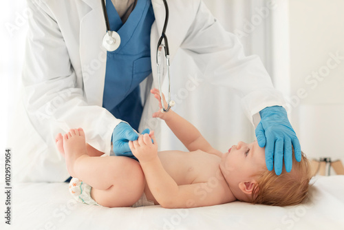 Healthcare for babies. Pediatrician examining little kid girl, touching her forehead during checkup in clinic
