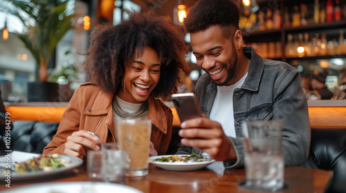 A couple sits at a warmly lit restaurant, sharing a meal and looking at their smartphone with laughter. They enjoy each other company in a vibrant atmosphere - Generative AI