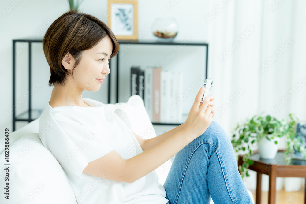 リビングでスマホを操作する女性 リビングでスマホを操作する女性