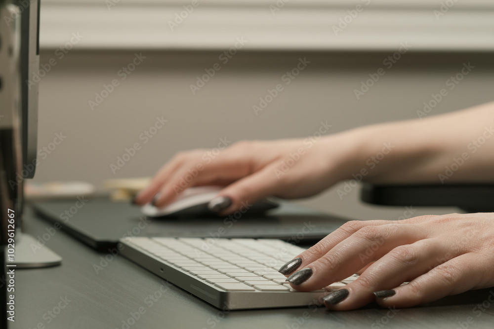 A woman is typing on a keyboard with a mouse A woman is typing on a keyboard with a mouse