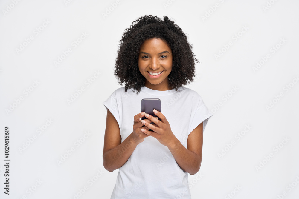 Young happy African gen z model standing isolated on white background looking at camera holding smartphone. Smiling Afro American woman using mobile cell phone advertising social media apps. Young happy African gen z model standing isolated on white background looking at camera holding smartphone. Smiling Afro American woman using mobile cell phone advertising social media apps.