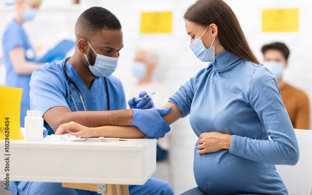 African American Doctor Giving Coronavirus Vaccine Injection Shot To Pregnant Woman, Wearing Protective Face Mask In Clinic Hospital. Corona Virus Vaccination, Patient Getting Vaccinated For Covid-19 African American Doctor Giving Coronavirus Vaccine Injection Shot To Pregnant Woman, Wearing Protective Face Mask In Clinic Hospital. Corona Virus Vaccination, Patient Getting Vaccinated For Covid-19