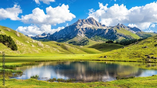 Serene mountain landscape with a reflective pond and lush greenery under a blue sky.