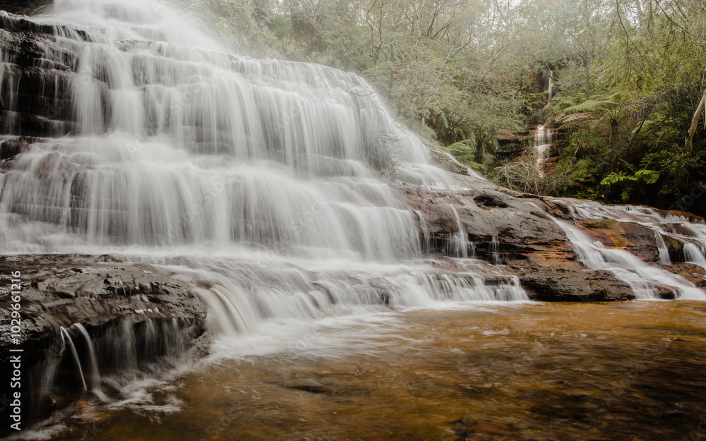 Tiers of cascading mountain water over rocks into a shallow pool Tiers of cascading mountain water over rocks into a shallow pool