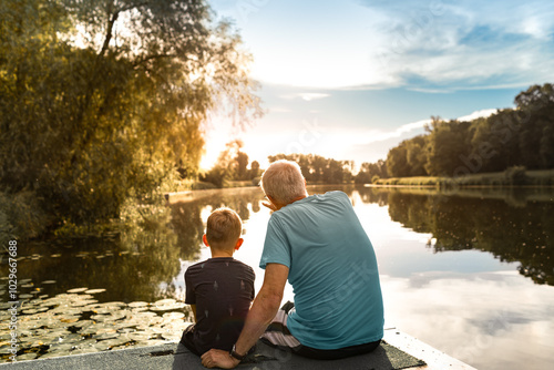 Foto Grandfather and grandson sitting on a dock by a lake watching beautiful sunset,