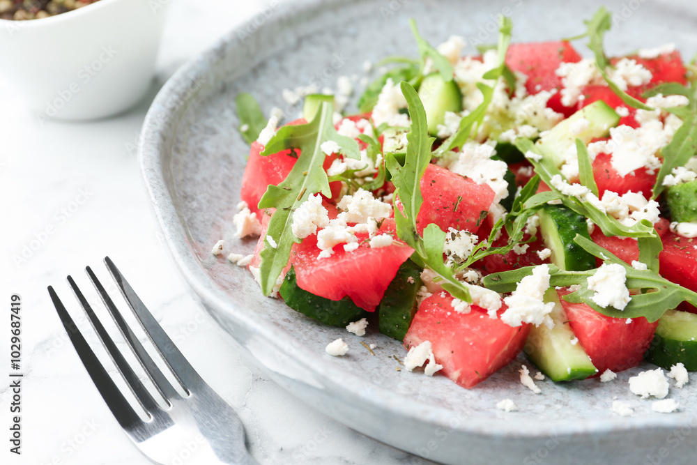 Delicious watermelon salad with feta cheese, cucumber and arugula served on white marble table, closeup