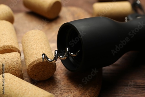 Wing corkscrew and corks on wooden table, closeup photo