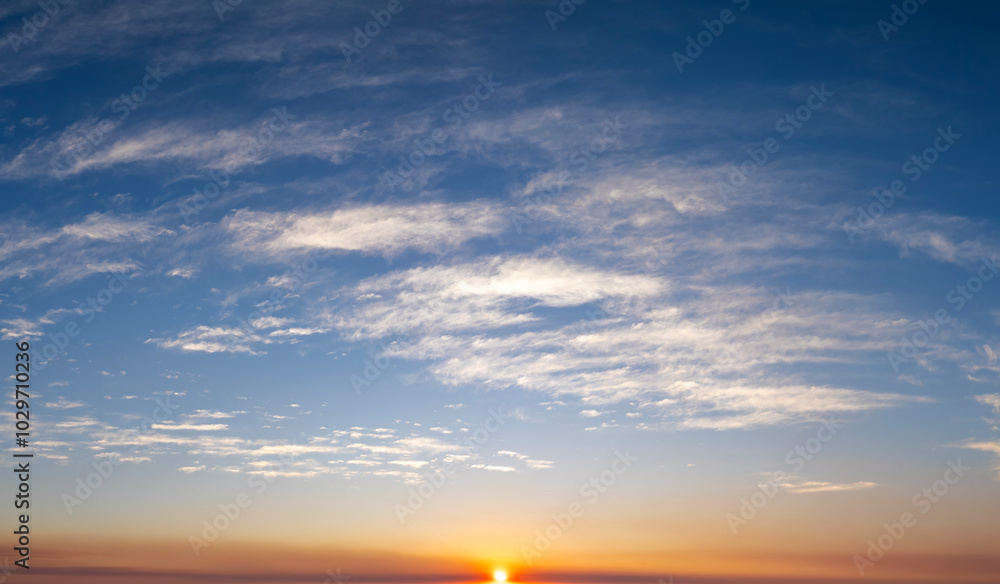 Colorful sunset sky with setting sun behind vivid orange and yellow clouds Colorful sunset sky with setting sun behind vivid orange and yellow clouds