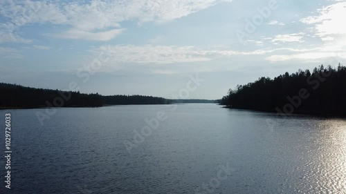 Low flight POV skims surface of tranquil lake in northern boreal forest photo