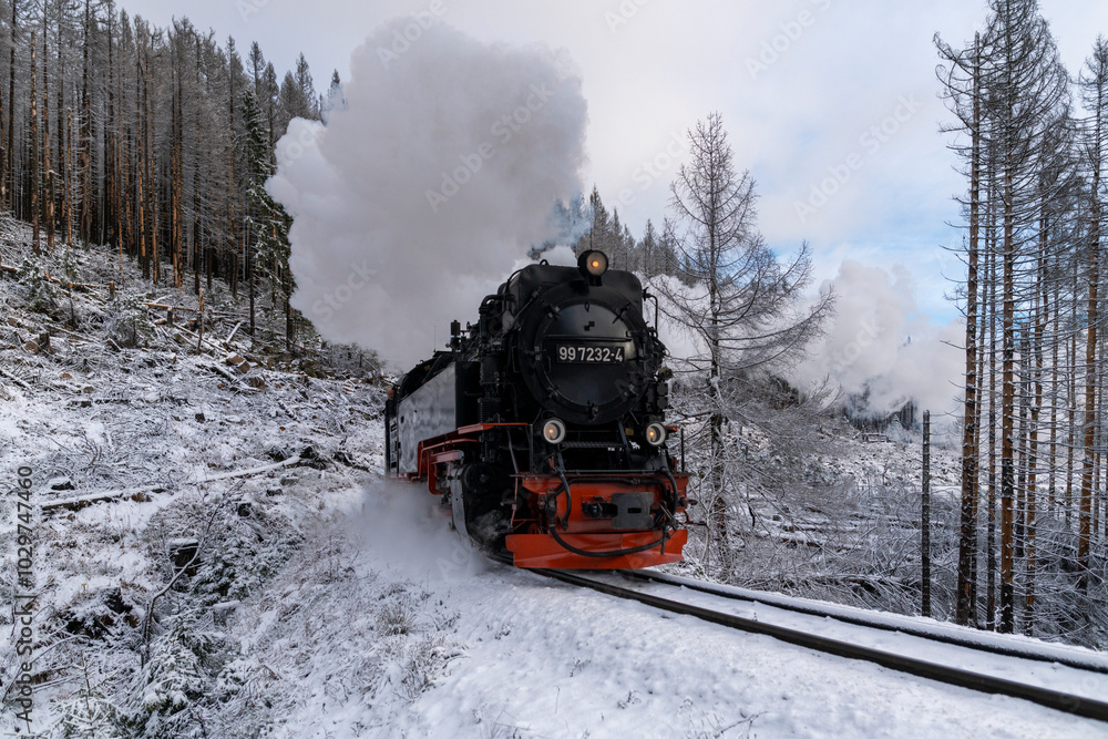 Close-up view of an old steam train moving through the forest on a snowy winter day Close-up view of an old steam train moving through the forest on a snowy winter day