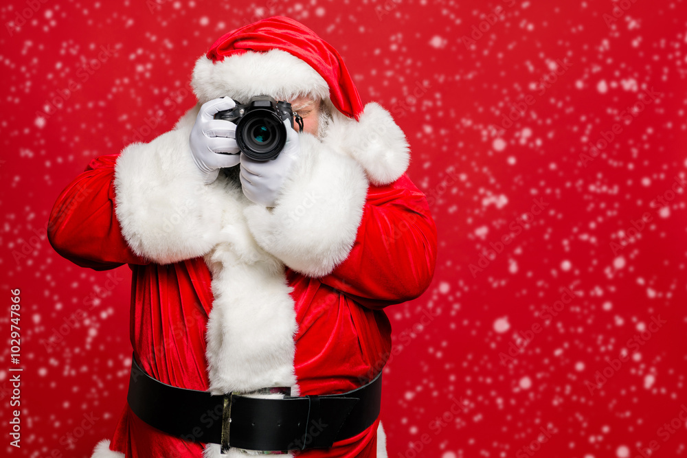 Portrait of focused elderly santa claus hipster take photo of his christmas time voyage abroad wear stylish costume belt gloves isolated over red background Portrait of focused elderly santa claus hipster take photo of his christmas time voyage abroad wear stylish costume belt gloves isolated over red background