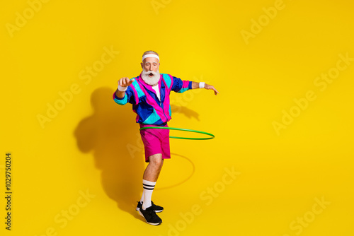 Full body portrait of eccentric aged man workout hula hoop empty space retro sportswear isolated on yellow color background