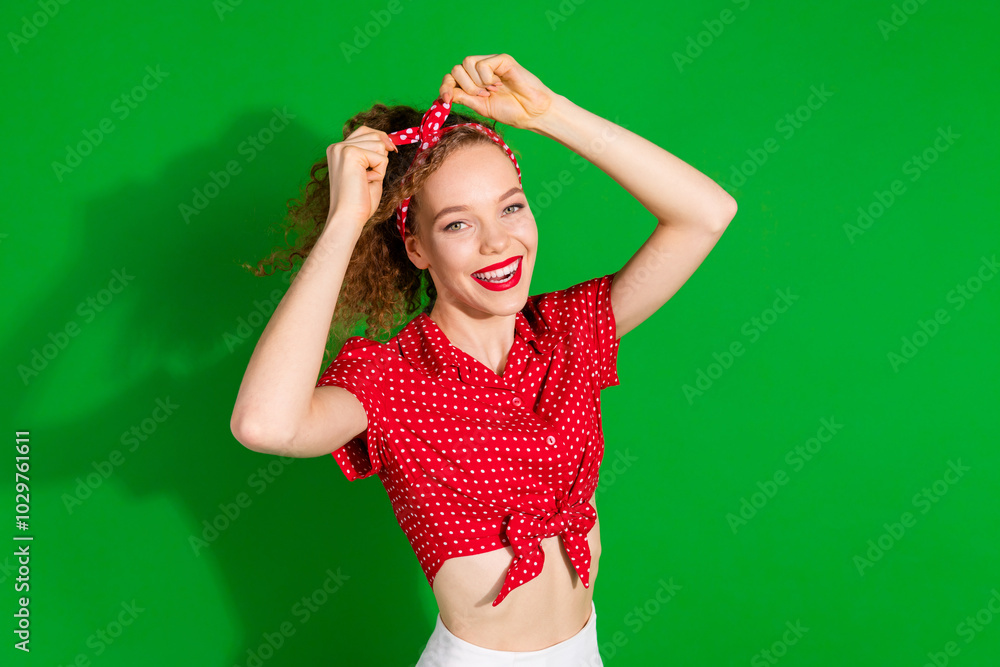 Photo portrait of pretty young girl fix headband wear trendy red retro outfit isolated on green color background Photo portrait of pretty young girl fix headband wear trendy red retro outfit isolated on green color background