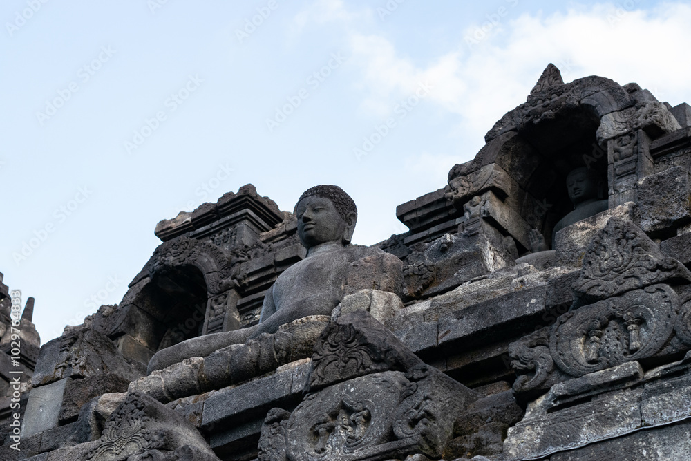 Ancient buddha statue is sitting peacefully on the upper level of borobudur temple in indonesia Ancient buddha statue is sitting peacefully on the upper level of borobudur temple in indonesia
