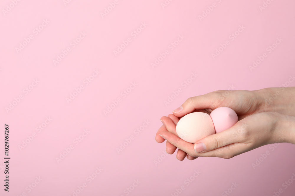 Makeup sponges in hand on pink background Makeup sponges in hand on pink background