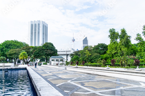 Tourist is walking in the garden of the kl city center, with the kuala lumpur tower in the photo