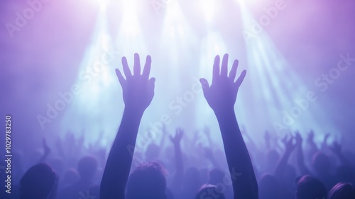 A crowd of people are at a concert, with their hands raised in the air. The atmosphere is lively and energetic, with everyone enjoying the music and the performance