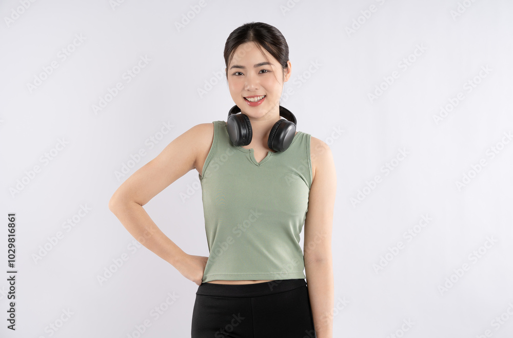 Portrait of young Asian girl wearing sportswear and headphones posing on white background Portrait of young Asian girl wearing sportswear and headphones posing on white background
