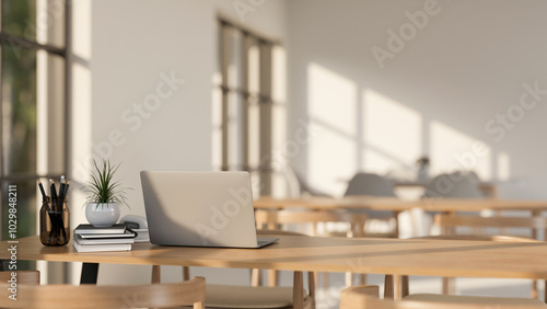 A laptop on a wooden table in a minimalist Scandinavian coffee shop co-working space or library.