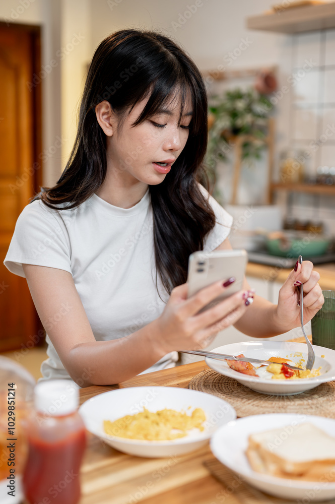 A woman is enjoying scrolling through her social media on her phone while eating in the kitchen. A woman is enjoying scrolling through her social media on her phone while eating in the kitchen.