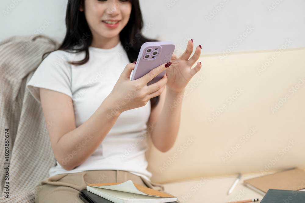 A close-up of a beautiful woman using her smartphone while sitting on a sofa in the living room. A close-up of a beautiful woman using her smartphone while sitting on a sofa in the living room.