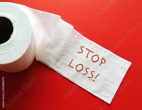 Toilet paper roll on red background with handwriting STOP LOSS, to buy or sell once stock reaches certain price, designed to limit investor loss on security position photo