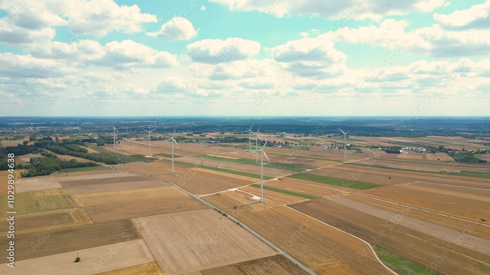 Aerial views of expansive farmland and wind turbines in an open landscape during a sunny afternoon Aerial views of expansive farmland and wind turbines in an open landscape during a sunny afternoon