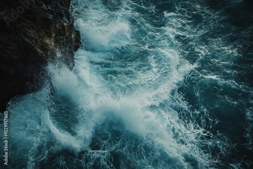 Aerial view of crashing waves against a rocky cliff.