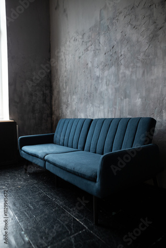 A cozy blue couch rests against a textured gray wall in a serene living space illuminated by natural light