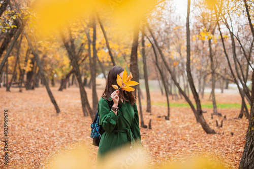 Front view of a young woman with a yellow leaf in front of her face