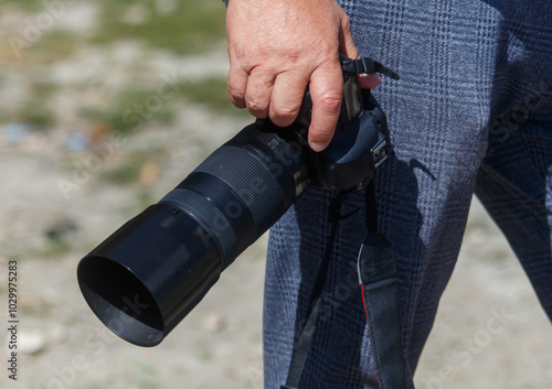 A man is holding a camera with a strap around his arm