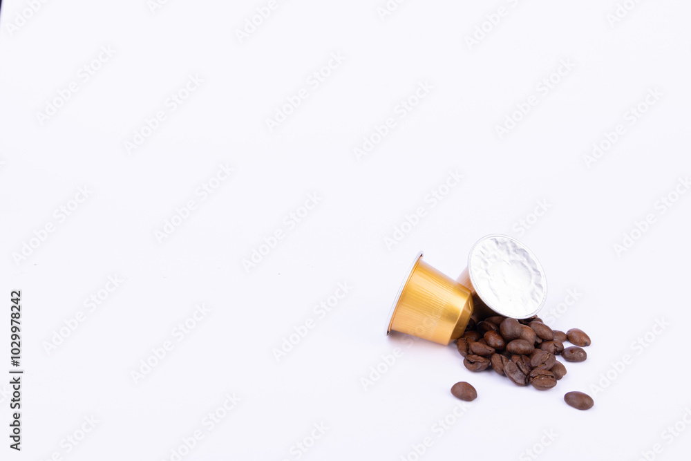Elegant Gold Coffee Capsules with Roasted Beans on White Elegant Gold Coffee Capsules with Roasted Beans on White