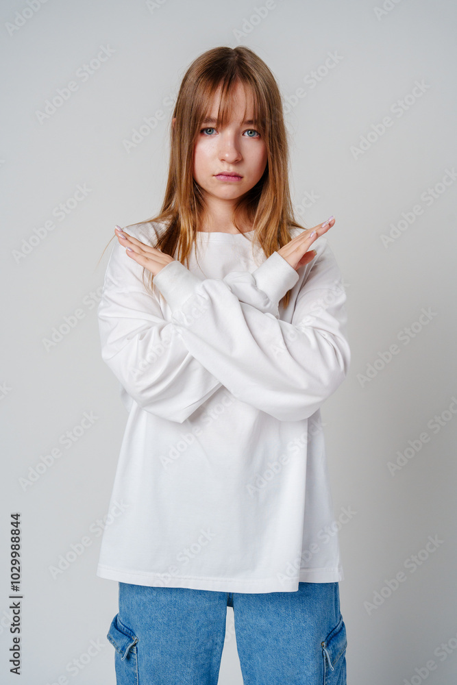 Young woman with long hair confidently poses with crossed arms against a plain background Young woman with long hair confidently poses with crossed arms against a plain background