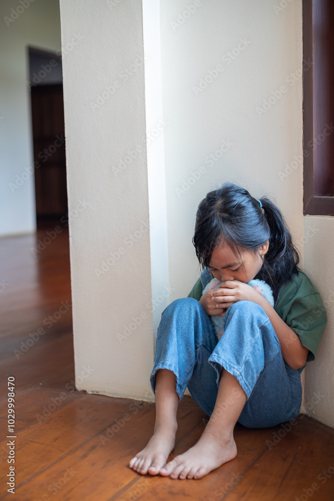 A young girl is sitting on the floor with a stuffed animal in her hand A young girl is sitting on the floor with a stuffed animal in her hand