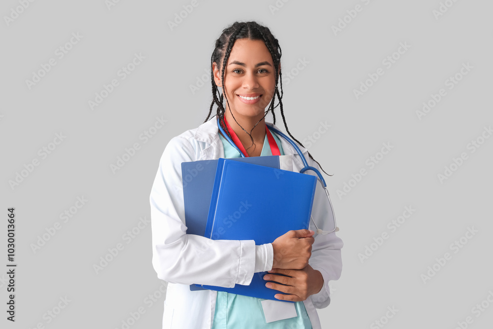 Young African-American female doctor with stethoscope and documents on white background Young African-American female doctor with stethoscope and documents on white background