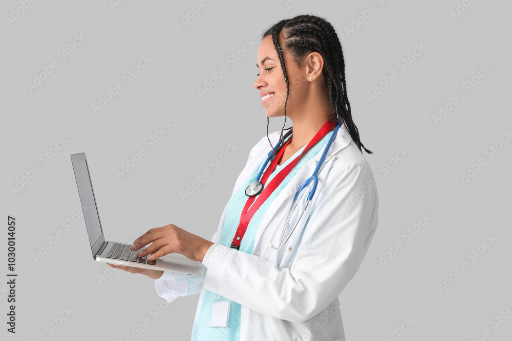 Young African-American female doctor with stethoscope and laptop on white background Young African-American female doctor with stethoscope and laptop on white background