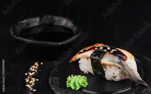 Delicious unagi nigiri sushi with ginger and soy sauce on black background photo