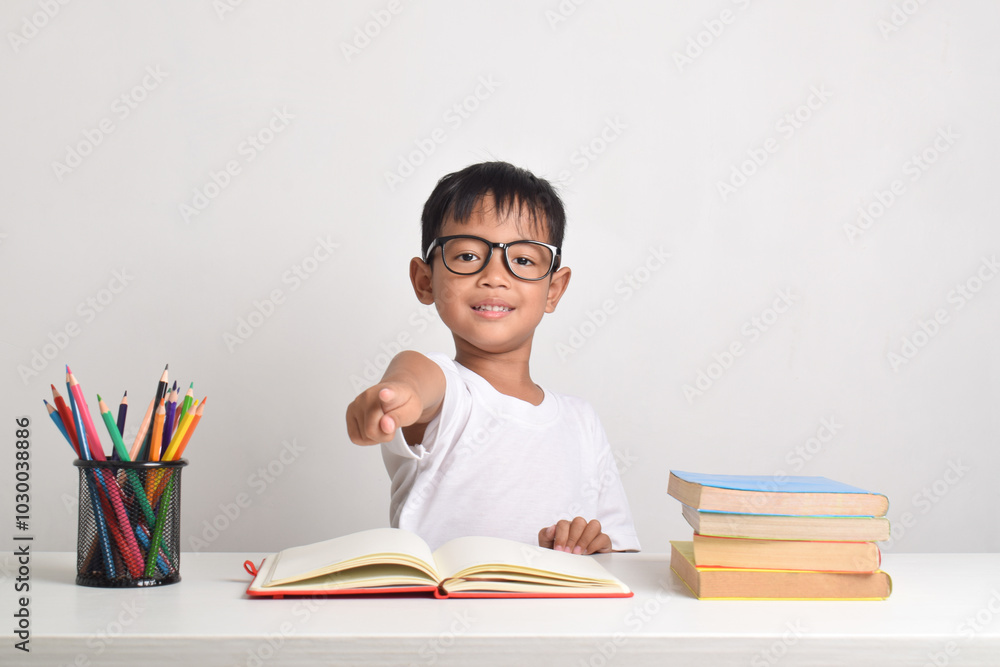 Portrait of an Asian boy studying isolated on a white background. Finger pointing at the camera