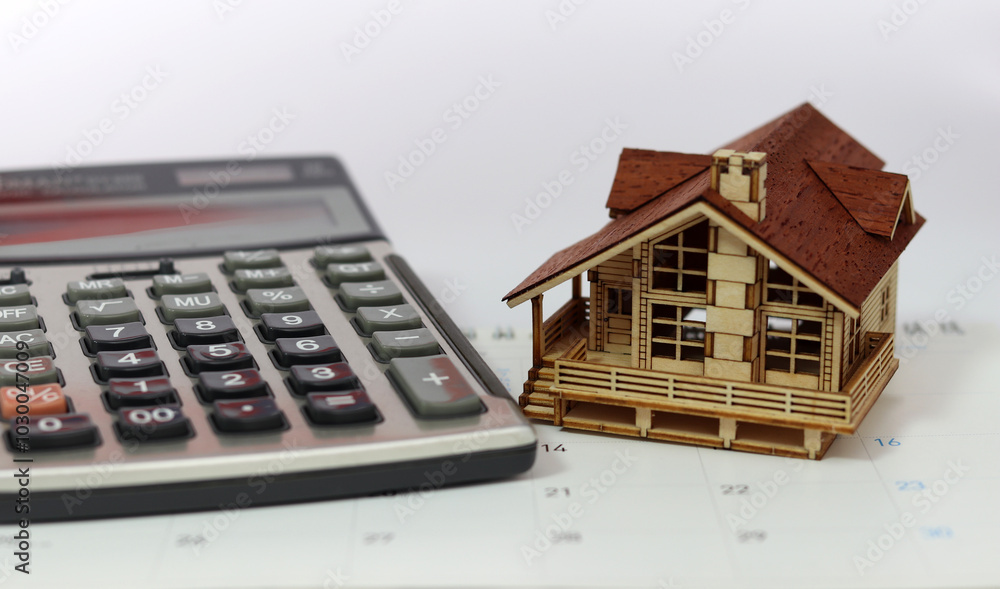 A calculator and a wooden house are placed on the calendar. Business investment and real estate concepts.
A calculator and a wooden house are placed on the calendar. Business investment and real estate concepts.