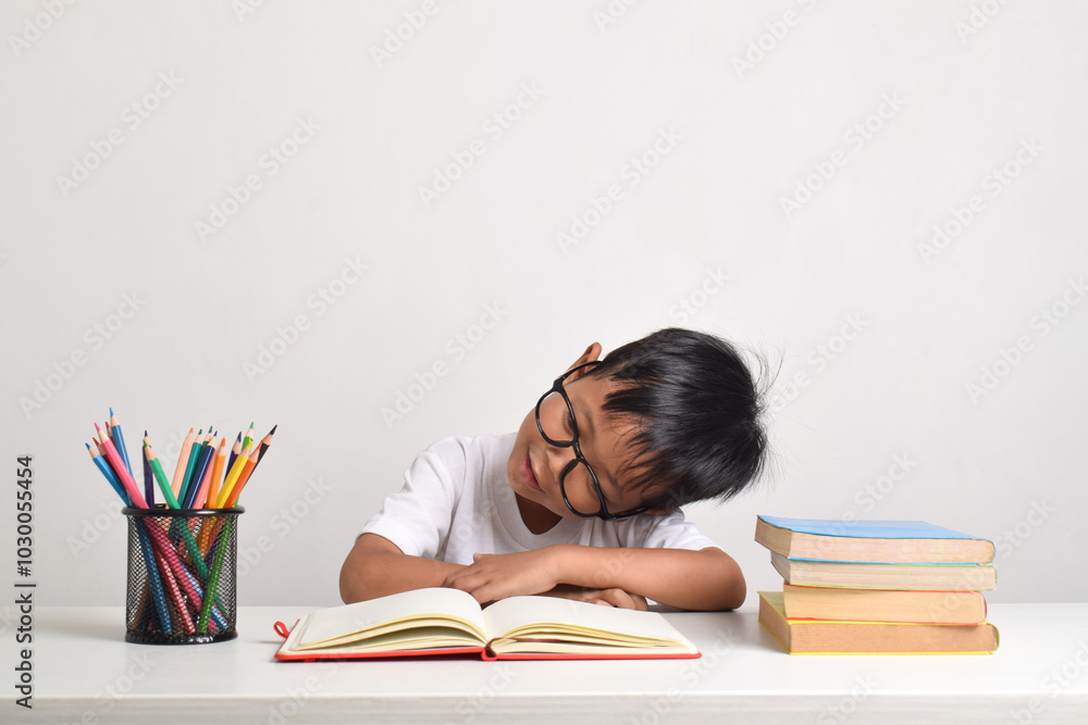 Portrait of an Asian boy studying isolated on a white background. The child is sleeping because he is tired from studying Portrait of an Asian boy studying isolated on a white background. The child is sleeping because he is tired from studying