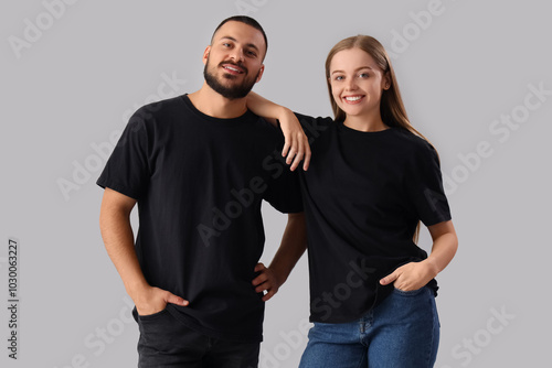 Young couple in stylish black t-shirts on grey background photo