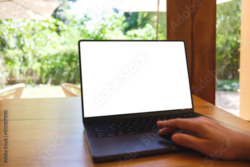 Mockup image of a woman using and touching on laptop computer with blank white desktop screen on wooden table