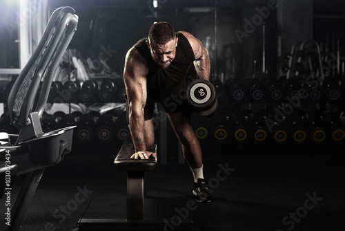 Obraz na płótnie Muscular man having training with weights. Brutal strong athletic men pumping up muscles workout. Concept bodybuilder doing exercises in gym. w salonie