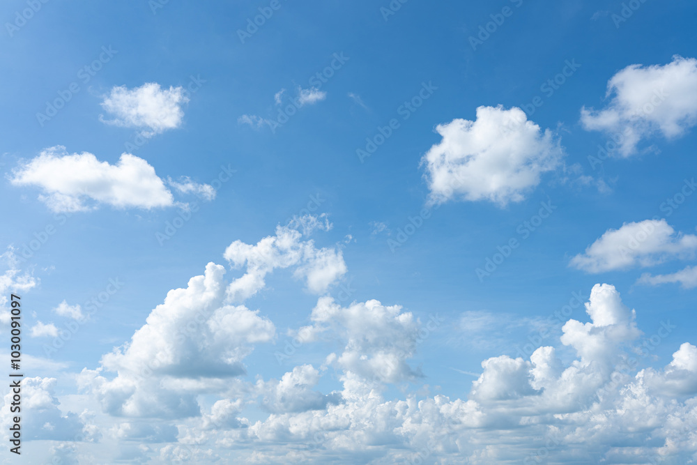 Fluffy white clouds float across a clear blue sky, creating a beautiful summer day Fluffy white clouds float across a clear blue sky, creating a beautiful summer day