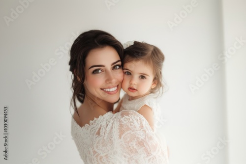 A beautiful woman smiling and holding her young daughter portrait photo happy.