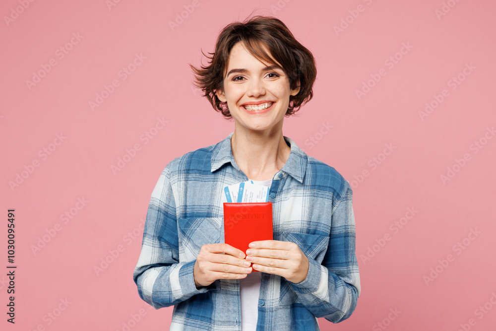Traveler smiling happy woman wears blue casual clothes hold passport ticket isolated on plain pink background. Tourist travel abroad in free spare time rest getaway. Air flight trip journey concept.